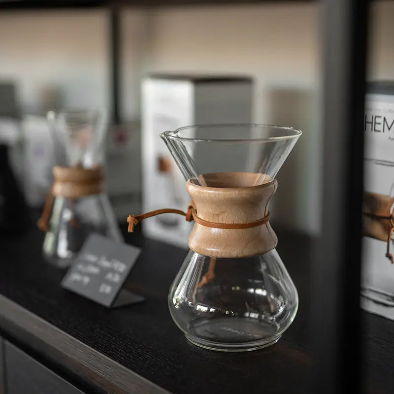 Leere Chemex-Glaskaraffe mit Holzmanschette im Regal eines Kaffeeshops