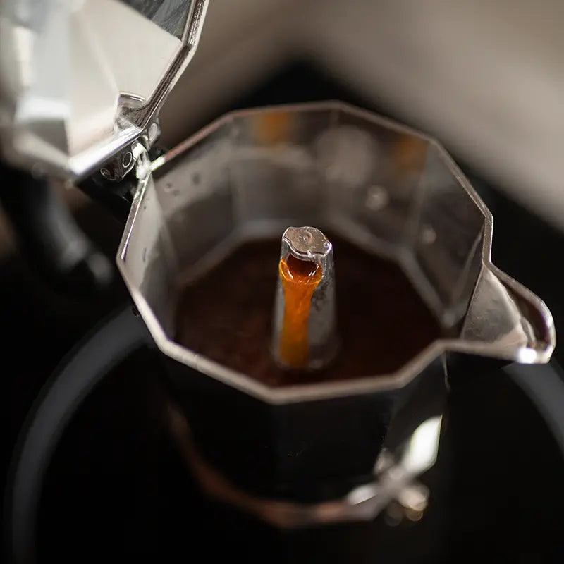 Frisch gebrühter Espresso läuft in geöffnetem Espressokocher