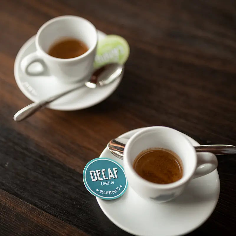 Zwei Espressotassen, davon eine mit Decaf Espresso Decaffeinato Etikett